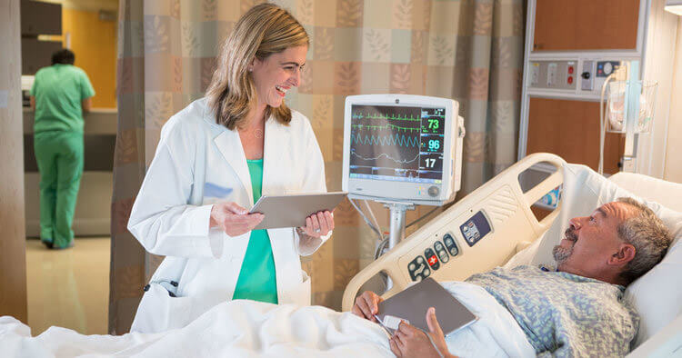 Mejorando la experiencia de paciente Doctora con tablet junto a un paciente en una habitacion de hospital
